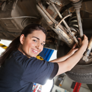 a smiling young woman working on a car